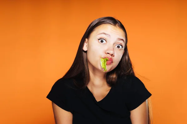 Молодая красивая девушка хочет похудеть, держит в руках и ест полезную пекинскую капусту — стоковое фото