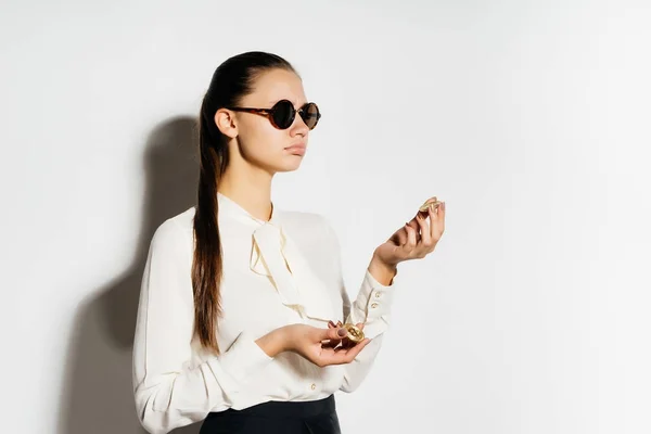 Jovem menina moderna bem sucedida em óculos de sol está segurando bitcoin em sua mão — Fotografia de Stock
