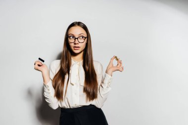 Gözlüklü genç modern bir başarılı kız altın bir bitcoin ve bir banka kartı tutuyor