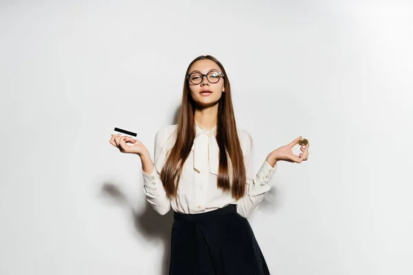Una joven chica de éxito moderno con gafas está sosteniendo un bitcoin de oro y una tarjeta bancaria — Foto de Stock
