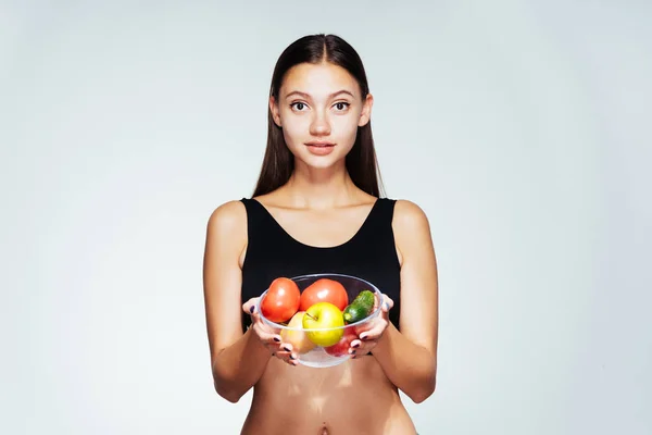Sportovní dívka v černý top drží desku s užitečné zeleniny a ovoce — Stock fotografie