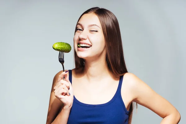 Jeune belle fille dans un haut bleu veut perdre du poids, mange un concombre utile — Photo