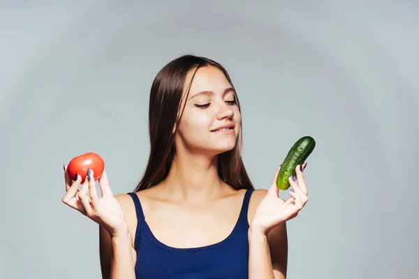 Mladá krásná dívka se chce zhubnout, drží v ruce užitečné rajče a okurka — Stock fotografie