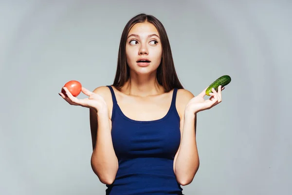Une jeune belle fille veut perdre du poids, tient dans sa main une tomate et un concombre utiles — Photo