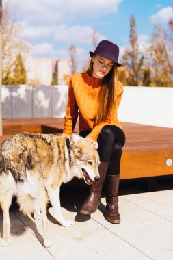 trendy bir turuncu kazaklı genç güzel kızıl saçlı kız parkta onun köpek ile yürüyor