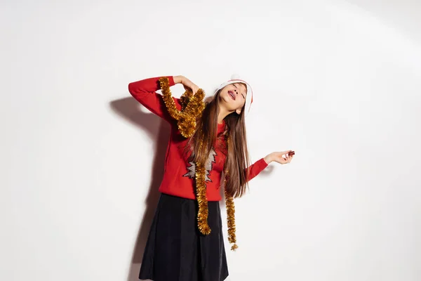 Genç güzel kız yılbaşı ve boynunda kırmızı bere ve altın tinsel giyen Noel kutluyor — Stok fotoğraf