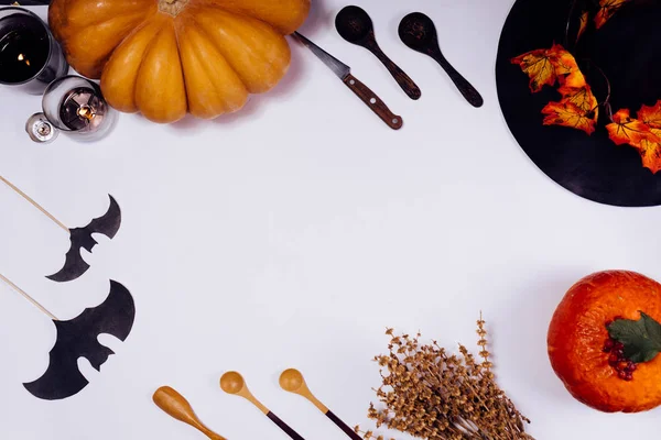 Samenstelling voor het verfraaien van een huis op halloween, op een witte tafel liggen oranje en gele pompoenen, brandende kaarsen en bladeren van de herfst geel — Stockfoto