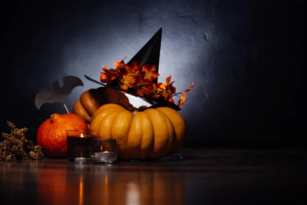 Uma composição para decorar uma casa para o dia das bruxas, abóboras de laranja, um grande chapéu de bruxa preta e velas acesas — Fotografia de Stock