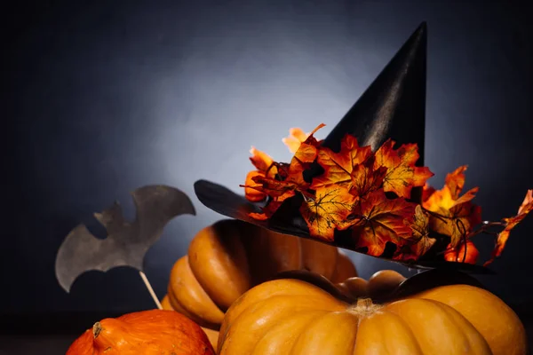 Een compositie voor het versieren van een huis voor halloween, oranje pompoenen, een grote zwarte heks hoed — Stockfoto