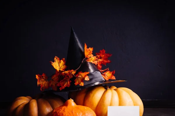 En komposition för att dekorera ett hus för halloween, ligga orange och gula pumpor, en stor svart häxa hatt — Stockfoto
