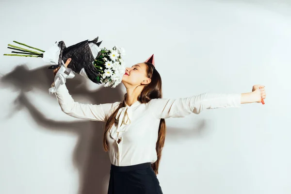 Giovane bella ragazza felice che celebra qualcosa, tenendo un grande mazzo di fiori bianchi, sorridente, sulla sua testa un cappello rosso festivo — Foto Stock