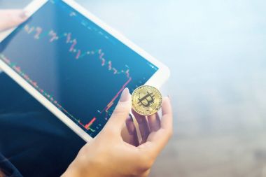 Modern başarılı kız altın bir bitcoin ve bir tablet grafikler Kripto para birimi ile tutar
