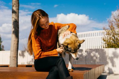 şık bir turuncu kazaklı genç güzel kızıl saçlı kız parkta onun köpek ile yürüyor,