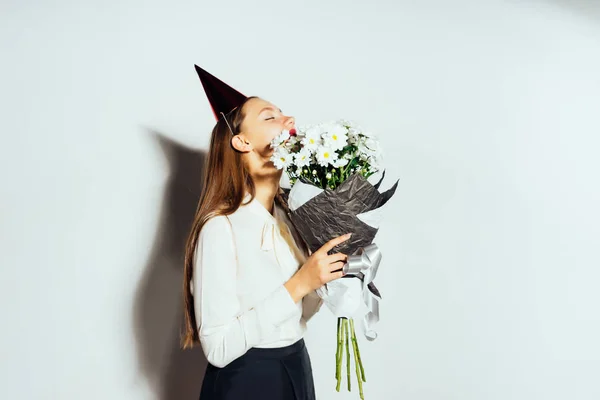 Glad flicka firar något, bära en mössa, innehar en stor bukett av vita blommor — Stockfoto