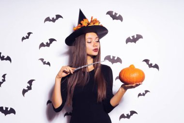 girl in a witch suit posing against the backdrop of bats