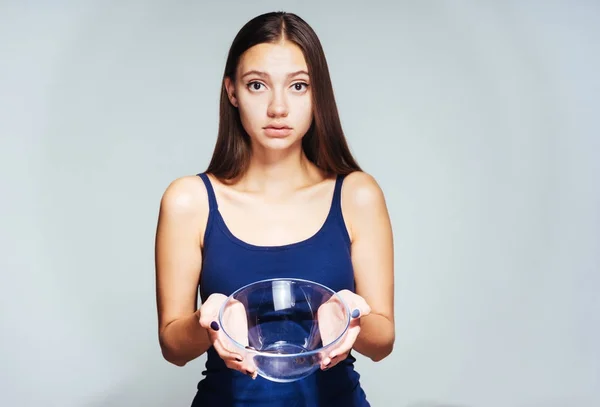 Menina frustrada segurando um prato vazio em suas mãos — Fotografia de Stock