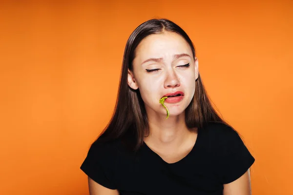Dziewczynka na pomarańczowym tle próbuje zjeść sałatkę — Zdjęcie stockowe