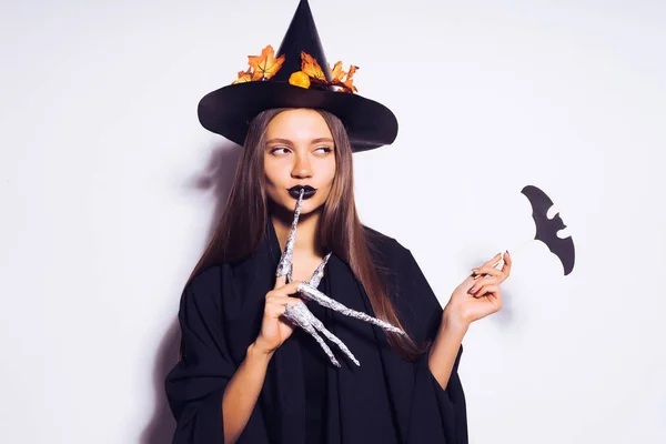 Het meisje in de witch's pak kijkt aan de zijkant blokkeren een gebaar naar iemand om te praten — Stockfoto