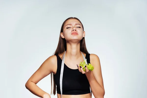 Девушка в спортивной форме держит лист салата в раке — стоковое фото