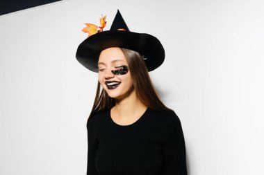 Beyaz bir arka plan üzerinde gülümseyen cadı elbiseli kız