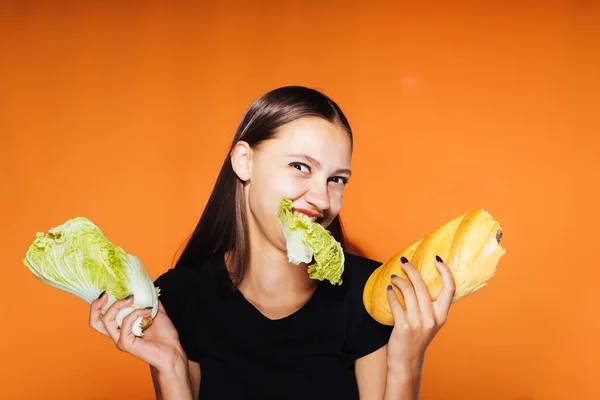 Mutlu kız bir salata ve ekmek tutan turuncu bir arka plan üzerinde — Stok fotoğraf