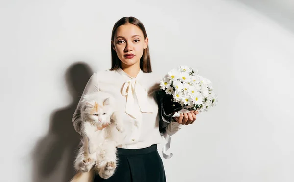 Menina séria segurando um buquê de flores e um gato — Fotografia de Stock