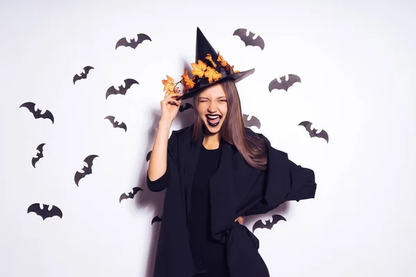 Meisje in een heks kostuum glimlachend in een omgeving van vleermuizen — Stockfoto