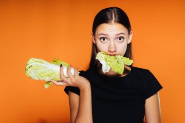 Kız marul yaprakları yeme turuncu zemin üzerine