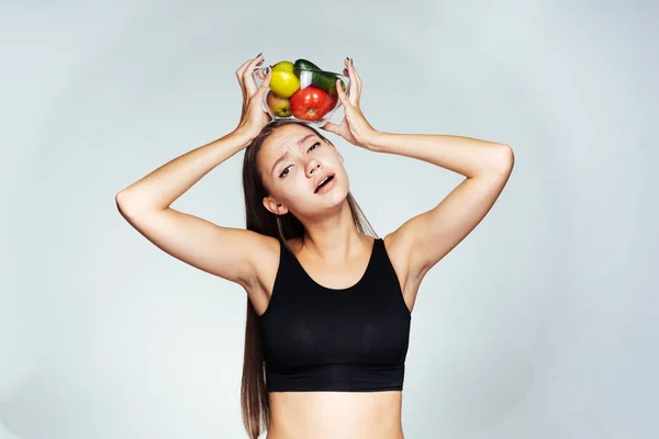 Frustrovaný dívka držící misku nad hlavou se zeleninou — Stock fotografie