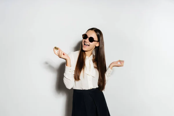 Glückliches Mädchen mit schwarzer Brille hält eine Münze auf weißem Hintergrund — Stockfoto