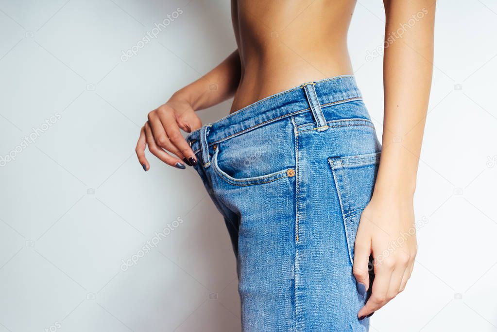 the girl is pleased with the size of her waist comparing with old jeans