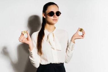 beyaz gömlek ve siyah gözlük genç modern bir başarılı kız altın bitcoin onun elinde tutuyor
