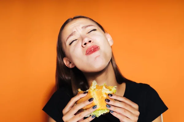 Krásná dívka jí škodlivé burger a trpí proto, že chce zhubnout, ale nemůže — Stock fotografie