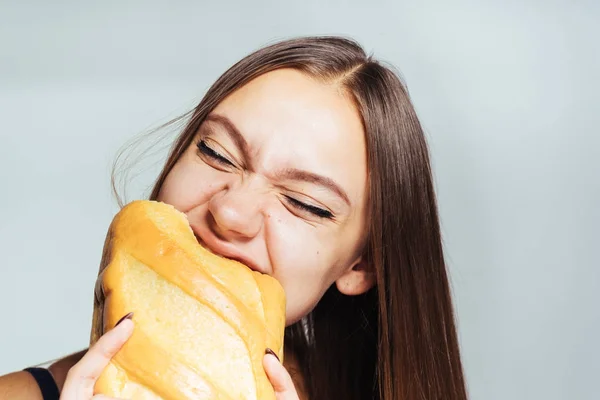Mladá dívka sedí na dietu, ale spadl a dychtivě jí nezdravé bílý chléb — Stock fotografie