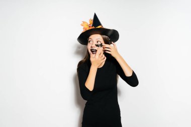 büyük bir siyah şapka bir genç gülmek cadı Cadılar Bayramı, onun gözleri Siyah Silikon yamalar altında Tutkallar için hazırlar