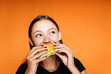 genç bir kız hevesle zararlı kalori hamburger yiyor ve onun sağlığı hakkında düşünmüyor