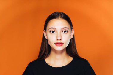 temiz cilt ve uzun saçları siyah T-shirt turuncu bir arka plan üzerinde poz içinde genç güzel kız