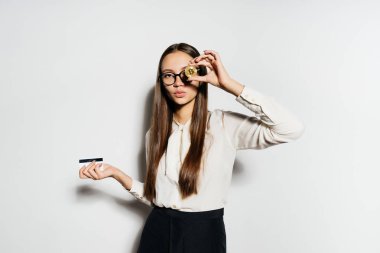 bir genç başarılı kız beyaz bir gömlek ve gözlük bir altın bikoin ve banka kartı tutuyor