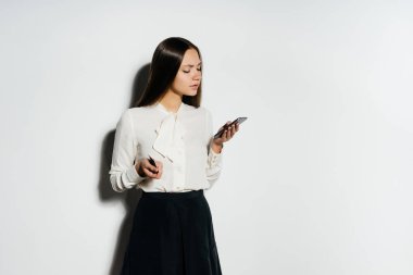 Genç modern ciddi kız Beyaz gömlekli bir altın bitcoin elinde tutan, onun smartphone görünüyor ve Kripto Döviz Alım çalışmaları