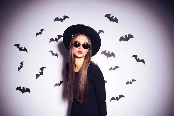 Belle fille gothique sexy en vêtements noirs et un grand chapeau de sorcière noire, lunettes de soleil envoie un baiser d'air — Photo
