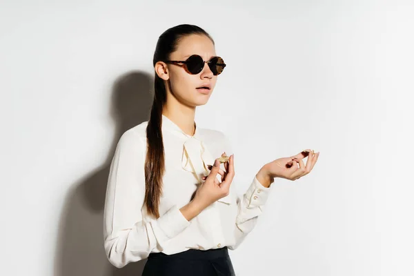 Uma menina confiante bem sucedida em óculos de sol pretos está segurando bitcoins dourados em suas mãos — Fotografia de Stock