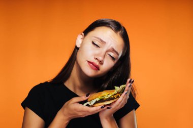 genç güzel kız bir diyet, oturur ama onun elinde büyük bir zararlı burger tutar ve bu yemek istiyor