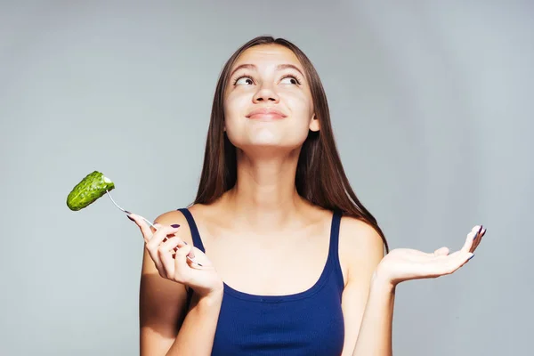 Jeune fille heureuse rêve de perdre du poids, tient une fourchette avec du concombre dans sa main — Photo