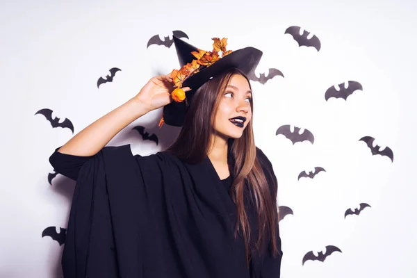 Hermosa chica sexy en la imagen de una bruja en Halloween, en su cabeza una gran bofetada negro decorado con hojas amarillas —  Fotos de Stock