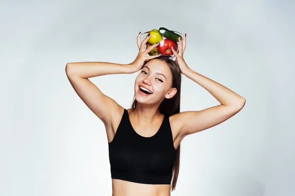 Feliz rindo menina esportes em um top preto segurando um prato com vegetais úteis e frutas — Fotografia de Stock