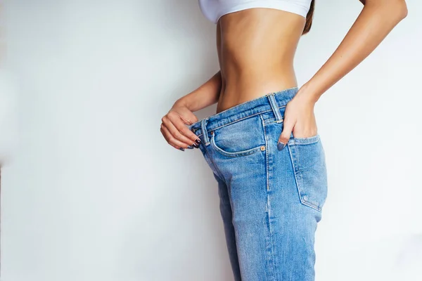 Menina esbelta em um top branco e jeans azul mostra o quanto ela perdeu peso — Fotografia de Stock