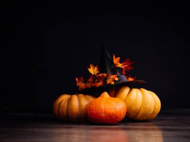 Cadılar Bayramı atmosfer yalan sarı ve turuncu kabak oluşturmak için sarı-kırmızı ile dekore edilmiş bir büyük kara cadı şapka akçaağaç yaprakları