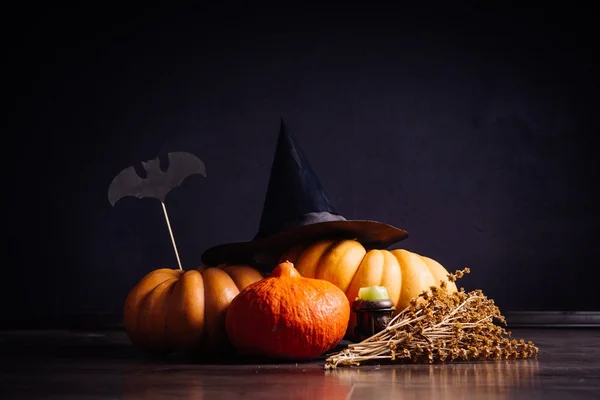 Als u wilt maken een halloween sfeer leugen gele en oranje pompoenen, ligt een zwarte heks hoed, een tak van droog gras — Stockfoto