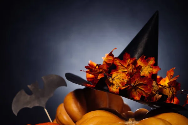Voor het versieren van het huis voor Halloween, gele en oranje pompoenen van de leugen en een zwarte heks hoed met gele bladeren — Stockfoto