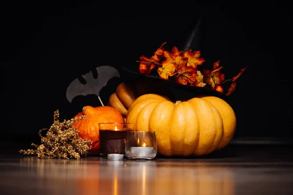 För att skapa en atmosfär av halloween lögn gula och orange pumpor, brinnande aromatiska ljus, ligger en gren av torrt gräs och ritningar av svarta fladdermöss — Stockfoto
